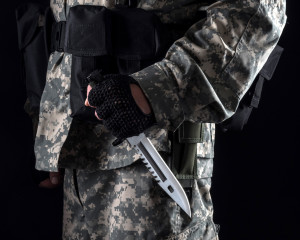 Military man with a knife in a hand on the black background